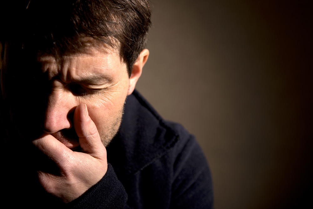 Tearful and distraught man, with his hand over his mouth.