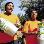 Women trained in using new storage technologies show off metal grain storage silos in Mnenia, Tanzania.