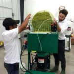 Edgar Ramirez, of Pleasant Valley Hops, and Kris Mattucci of the OAFVC pour ground-up hops cones into a pelletizer.