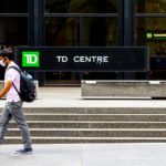 A man wearing a protective face mask walks by TD Bank in the financial district as phase 2 reopening from COVID-19 restrictions began in Toronto, June 24, 2020.