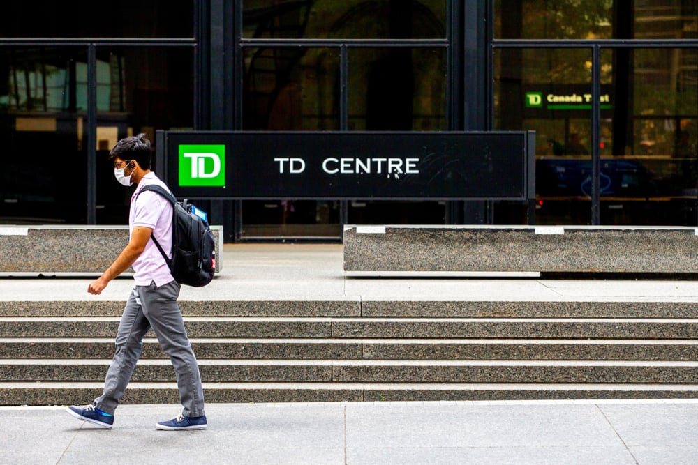 A man wearing a protective face mask walks by TD Bank in the financial district as phase 2 reopening from COVID-19 restrictions began in Toronto, June 24, 2020.