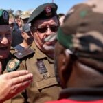 Men wearing what look like military uniforms speak with a member of the Economic Freedom Fighters (EFF) outside of the Senekal magistrate’s court at Senekal in South Africa’s Free State province on Oct. 16, 2020. (Photo: Reuters/Siphiwe Sibeko)
