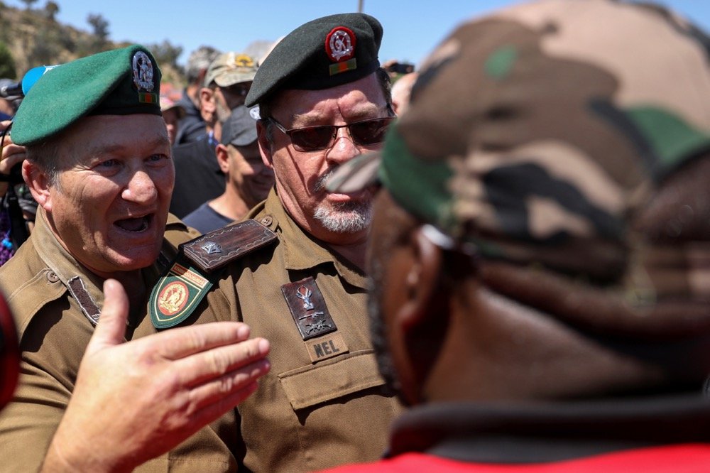 Men wearing what look like military uniforms speak with a member of the Economic Freedom Fighters (EFF) outside of the Senekal magistrate’s court at Senekal in South Africa’s Free State province on Oct. 16, 2020. (Photo: Reuters/Siphiwe Sibeko)
