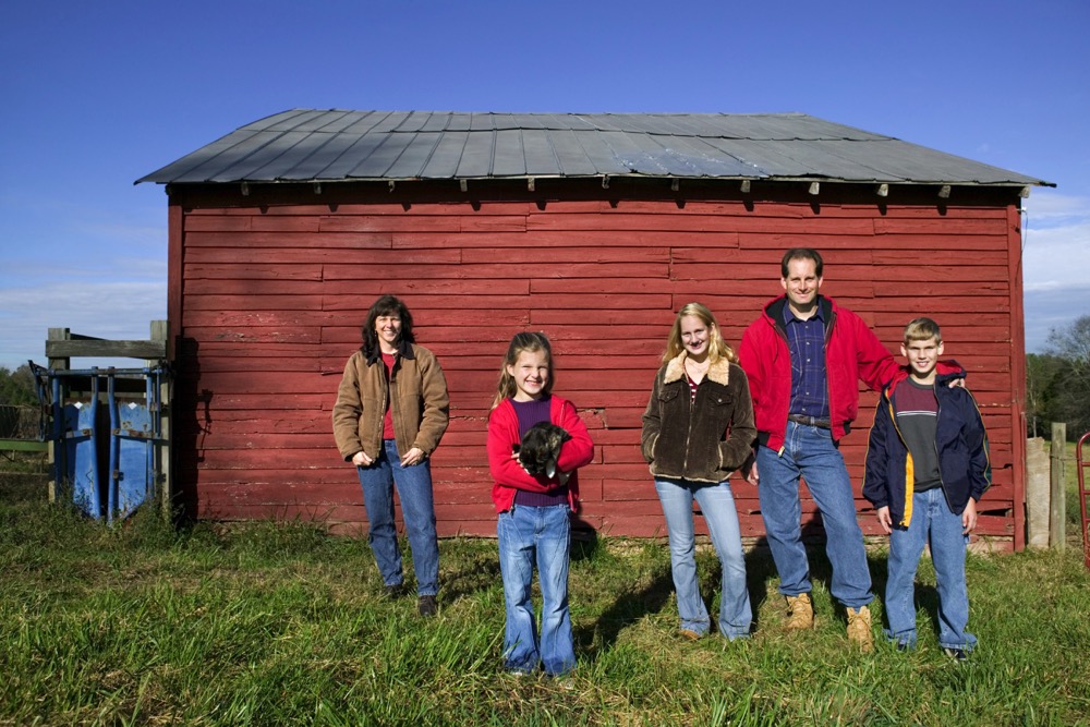 farm family beside a red barn