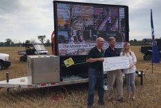 John Poel, left, provincial director to OSCIA's Heartland region, accepts a cheque from Trillium Insurance representatives Mike Brine and Angela De Groot. The donation was made Aug. 5 during a Compaction Day event at Rostock.