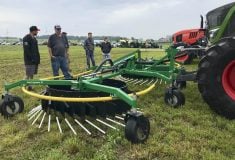 Aric Wilson of Leading Edge Equipment, left, discusses the Finnish-made, front-mounted Agronic rake during the recent Ontario Forage Expo near Paisley.