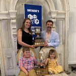 Jessica Kelly and Stewart Skinner hold their Ontario Outstanding Young Farmers award with their children Bryce, 7 and Mae, 3