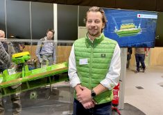 John Deere's Jonathan Edwards stands in front of the company's new Active Slope Adjustment for combine cleaning shoes at Agritechnica.