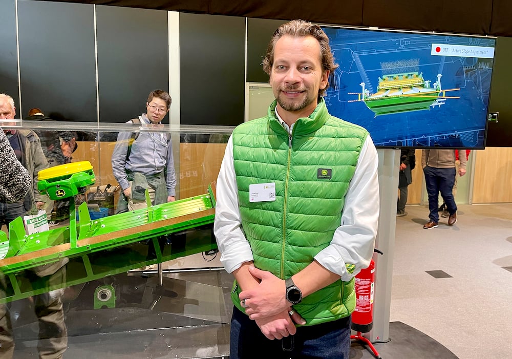 John Deere's Jonathan Edwards stands in front of the company's new Active Slope Adjustment for combine cleaning shoes at Agritechnica.