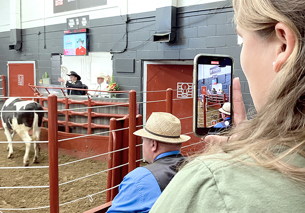 A woman films an auctioneer chanting on her phone