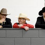 A line of men in cowboy hats over overlook the competion