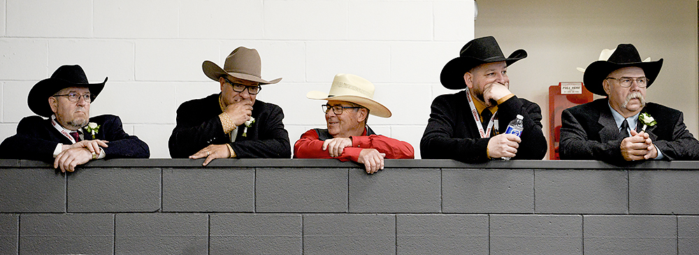 A line of men in cowboy hats over overlook the competion