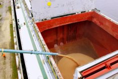 A ship being loaded with grain at port.