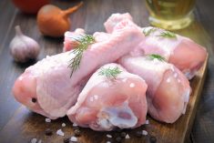 Chicken drumsticks seasoned with fresh rosemary and rock salt on a chopping board.