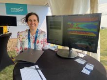 Heather Sanders of AgSenze stands in front of a computer display of her company's system at Ag in Motion 2025.