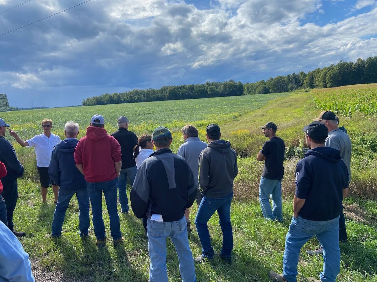 Farmer Harrison Burgsma, left in the white shirt, talks to a crowd of people in front a grassed waterway on a recent Ontario Soil Network tour of Huron County. Photo: John Greig