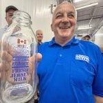 John Miller, proudly displays the Canadian Flag that adorns the smaller sized glass bottles for their premium Jersey milk products during a tour of the on-farm processing facility near Creemore, Ont. Photo Diana Martin