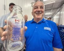 John Miller,  proudly displays the Canadian Flag that adorns the smaller sized glass bottles for their premium Jersey milk products during a tour of the on-farm processing facility near Creemore, Ont. Photo Diana Martin