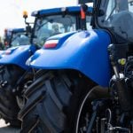 Close up on the fender of a blue tractor in a line of blue tractors.