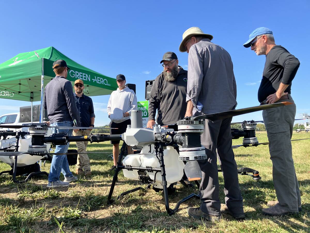 Warren Genick (centre) talks with attendees beside the DJI Agras T100 drone during the drone demonstration at Canada’s Outdoor Farm Show 2025 in Woodstock, Ontario. Photo: Greg Berg