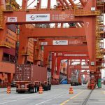 A truck carries a container near a cargo ship bound for Japan at the Centerm container ship terminal at the Port of Vancouver in Vancouver, British Columbia, Canada August 3, 2025.  REUTERS/Chris Helgren
