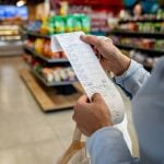 A person checks a list in a grocery store.