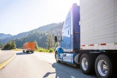 A blue semi truck with a trailor drives on the highway. Photo: Getty Images Plus
