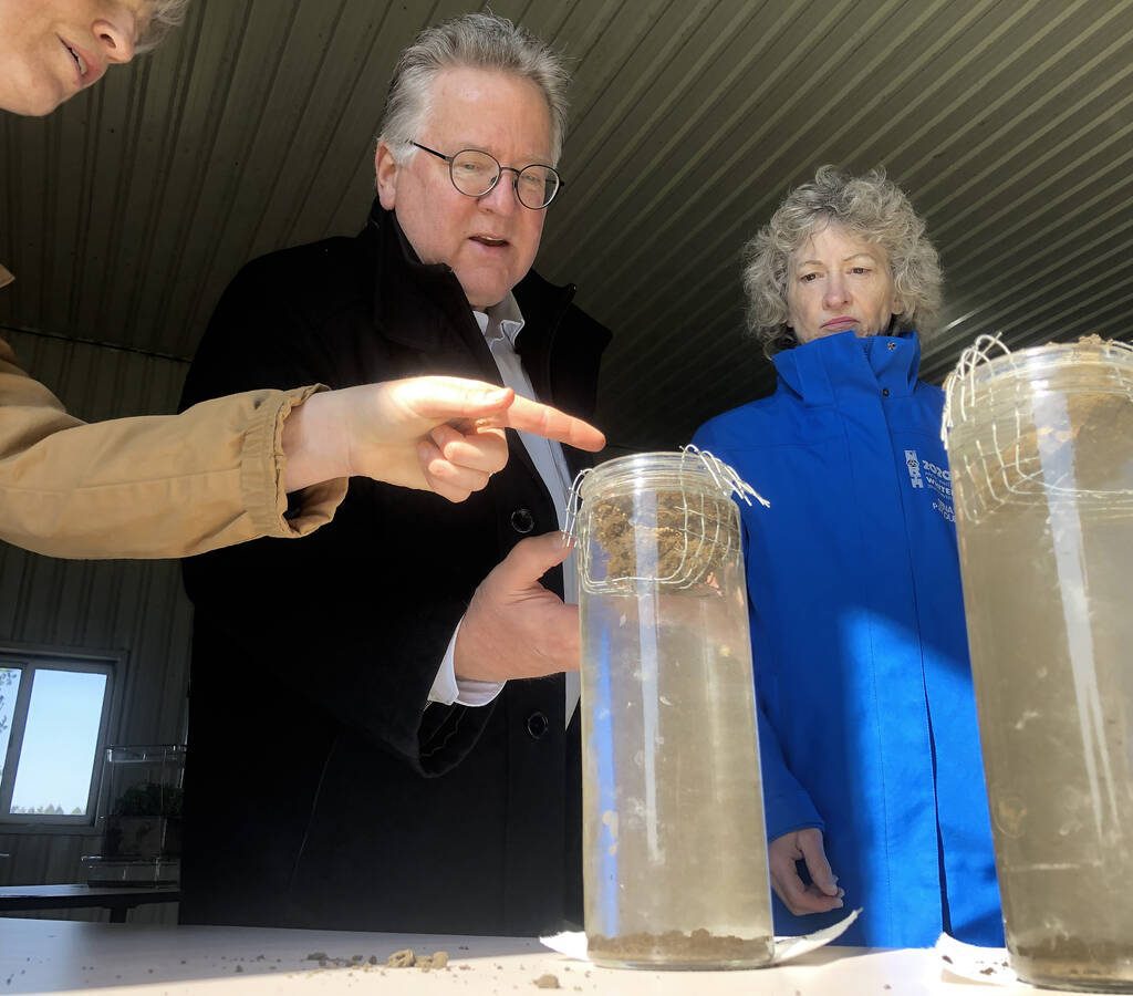 MANDATORY CREDIT: Diana Martin, Farmtario Under the direction of Heather White, Soils at Guelph, far left, Ontario Senator Rob Black, centre, and Yukon Senator Pat Duncan, right, compare the integrity of two soil samples gently laid mesh baskets to see which will hold their form and which will crumble in long tubes of still water.
