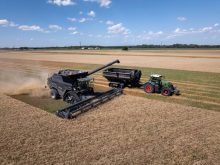 This image, taken during the 2024 AGCO Tech Day, shows PTx Trimble&rsquo;s OutRun solution in action: an autonomous Fendt tractor pulls a grain cart alongside an IDEAL combine during offloading.