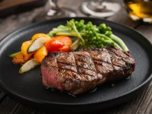 Grilled steak with vegetables on black plate