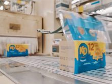 A conveyor belt carries blue and gold multi-pack boxes of Kraft Dinner to be sealed. Photo: Kraft Heinz video screengrab via YouTube