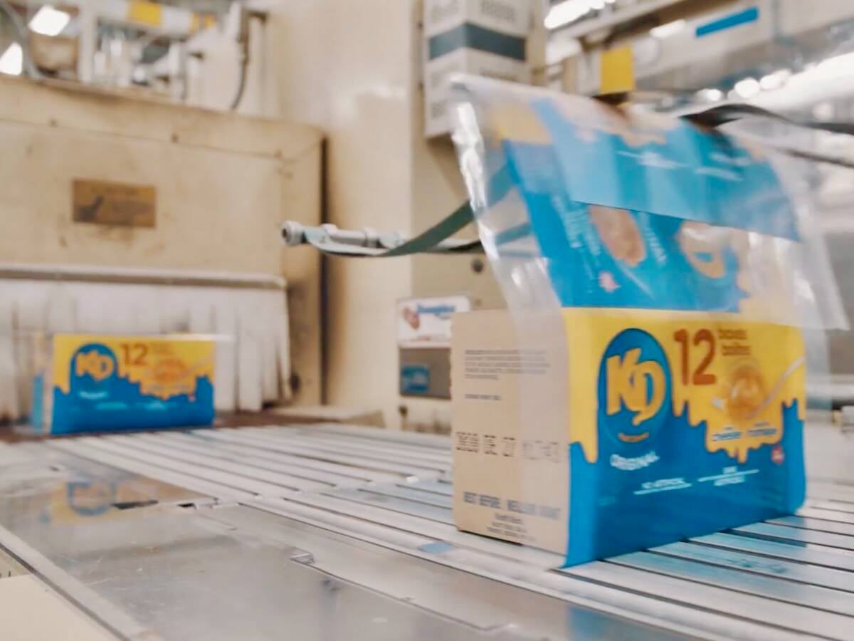 A conveyor belt carries blue and gold multi-pack boxes of Kraft Dinner to be sealed. Photo: Kraft Heinz video screengrab via YouTube